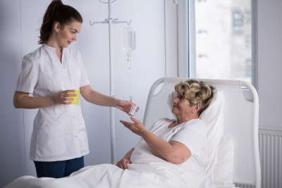 nurse giving medicine to senior patient